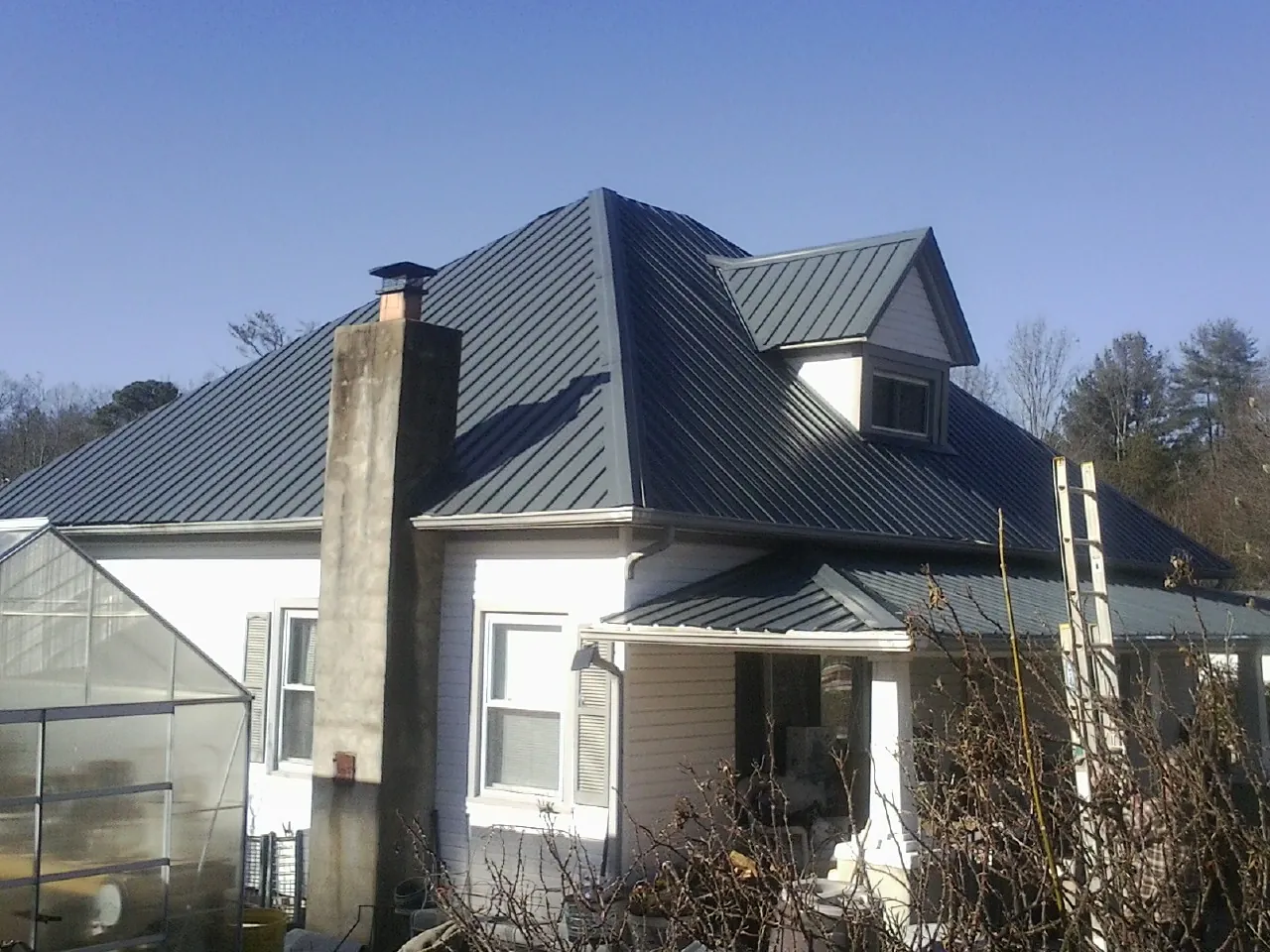Dark blue standing seam metal roof on a white farmhouse with dormer — Slate & Tile Roof Repair by Roofing Brothers in Pennville