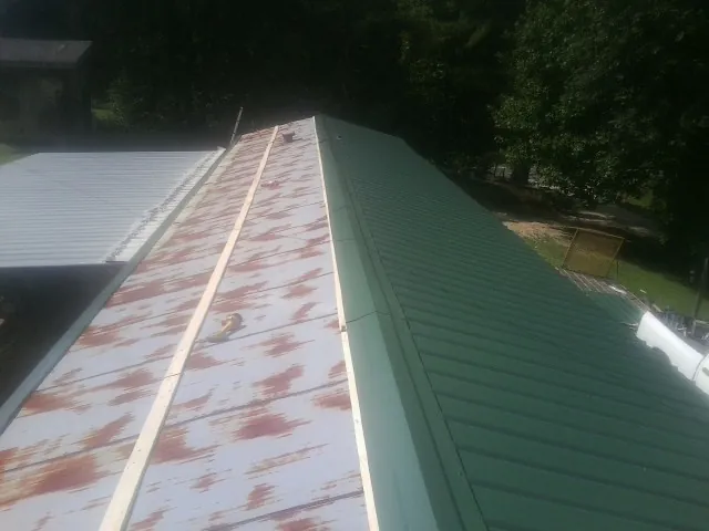 Old rusted panels beside newly installed green metal roofing — Wind Damage Roof Repair by Roofing Brothers in Pennville