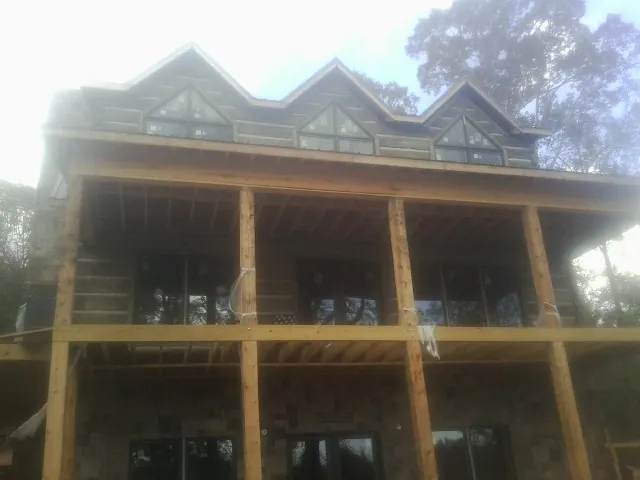 Dormers and porch framing on a large log home under construction — Roof Coating work by our crew in Pennville