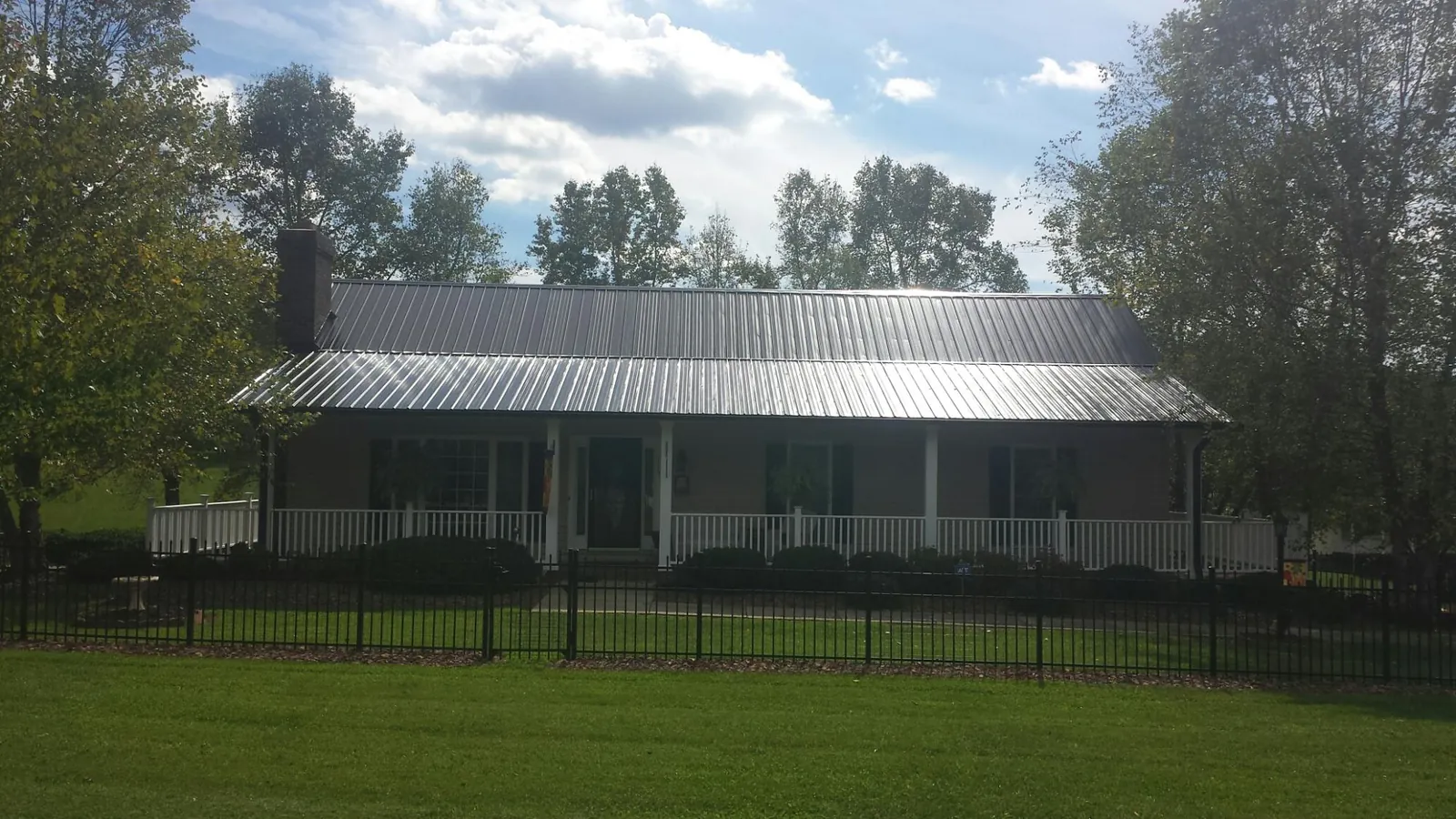 Gray metal roof on a brick ranch with a full width front porch — Gutter Guard Installation work by our crew in Pennville