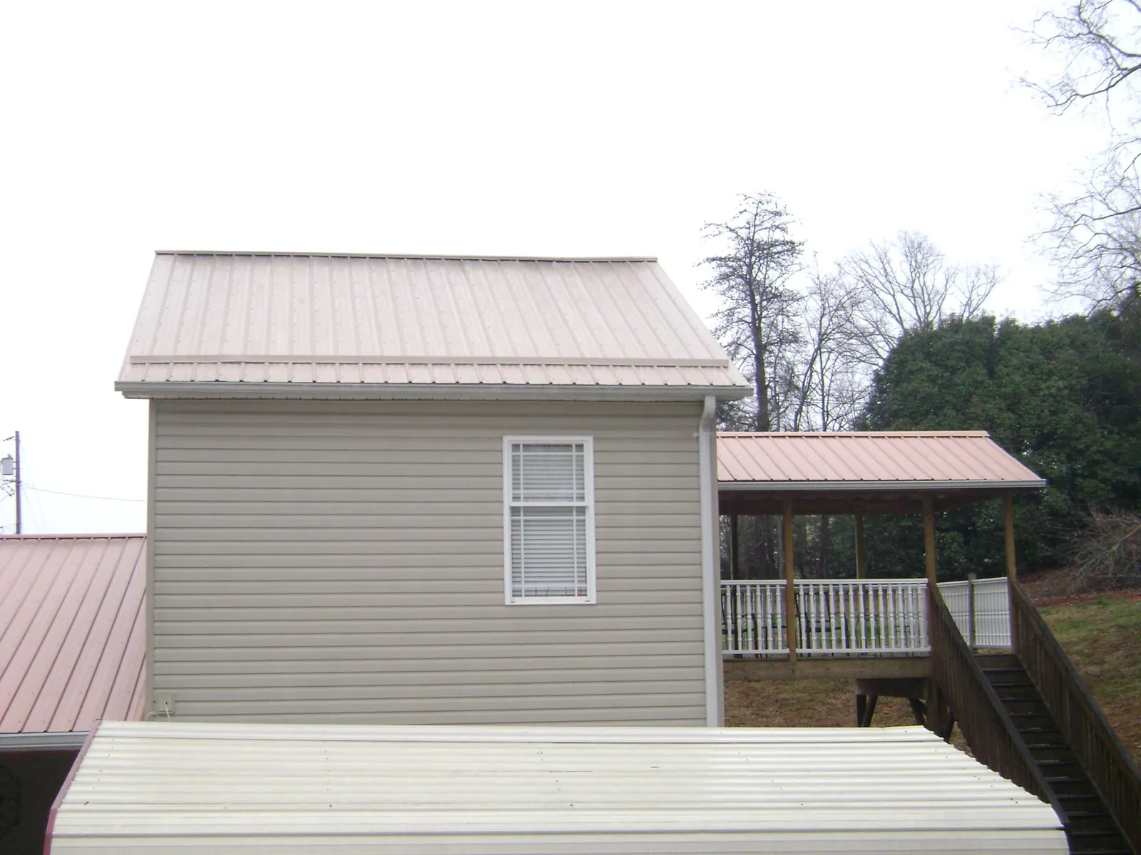 Tan metal roofs on a two story addition and attached porch, from a Roof Replacement job in Pennville