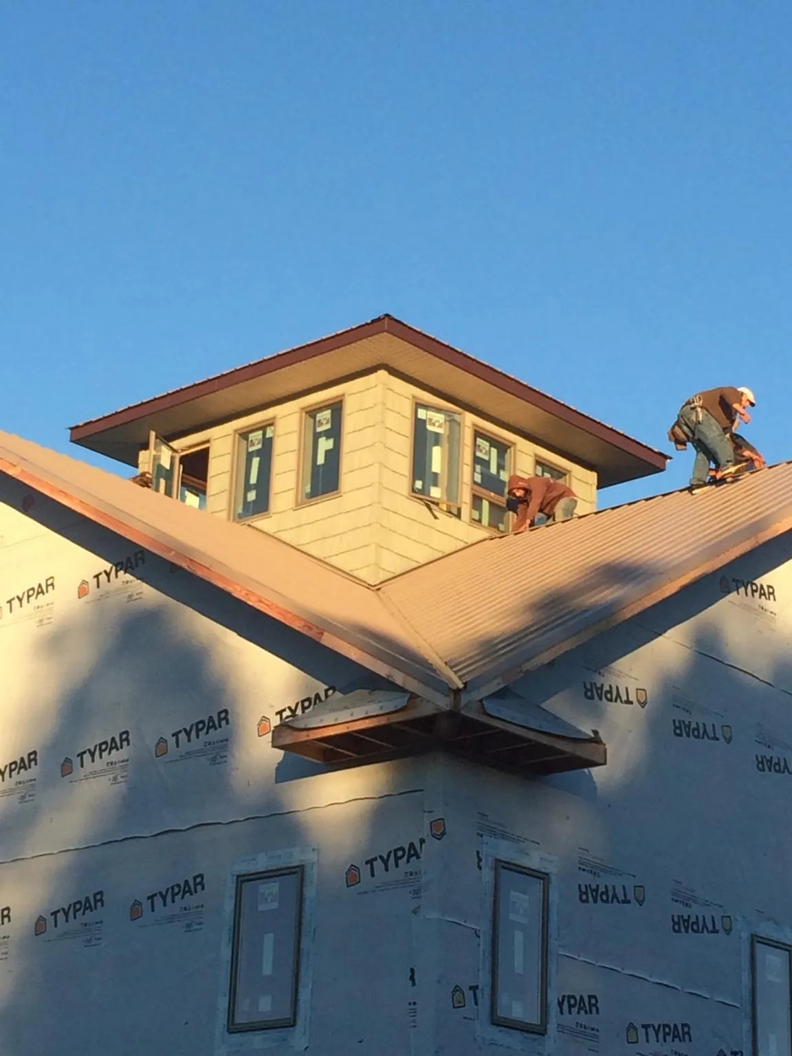 Roofers working around a rooftop cupola on a new metal roof at sunset — Roof Waterproofing in Pennville by Roofing Brothers